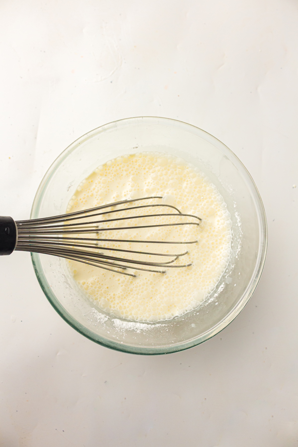 whisk in a glass bowl with whole milk, double cream, confectioners&rsquo; sugar, and vanilla extract