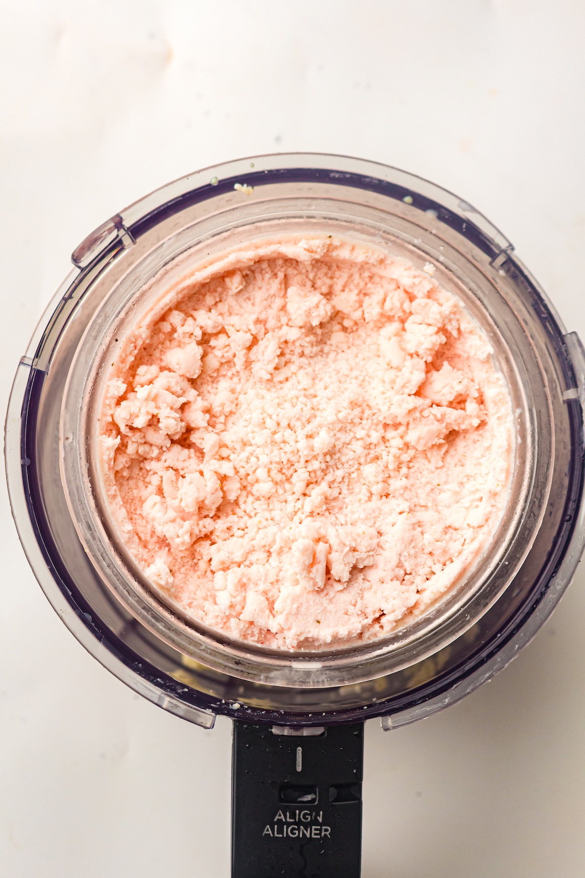 Top-down view of a clear container filled with light pink granular substance, attached to a black base labeled 'ALIGN ALIGNER,' set against a light background.
