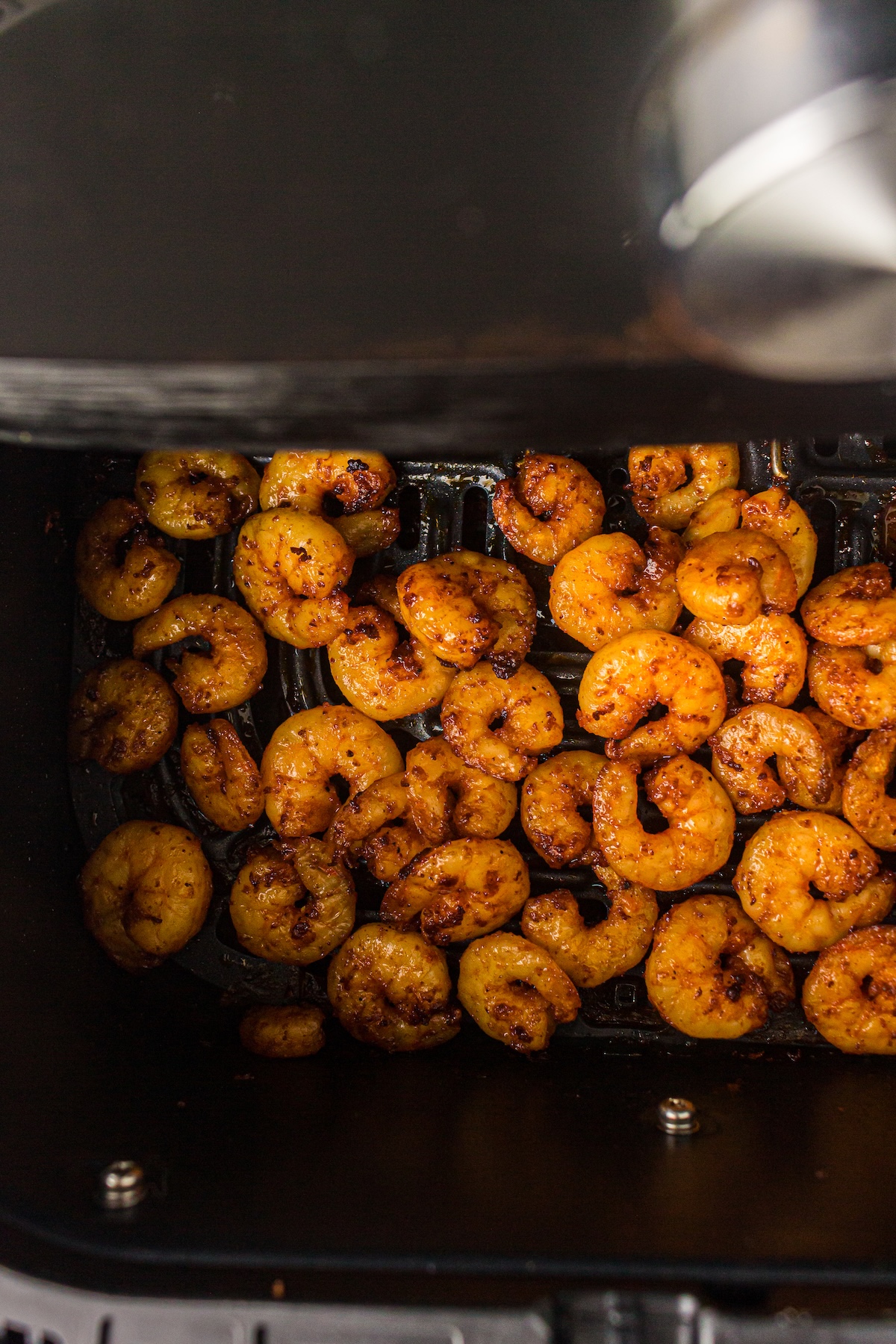 Juicy, seasoned shrimp in the basket of an air fryer