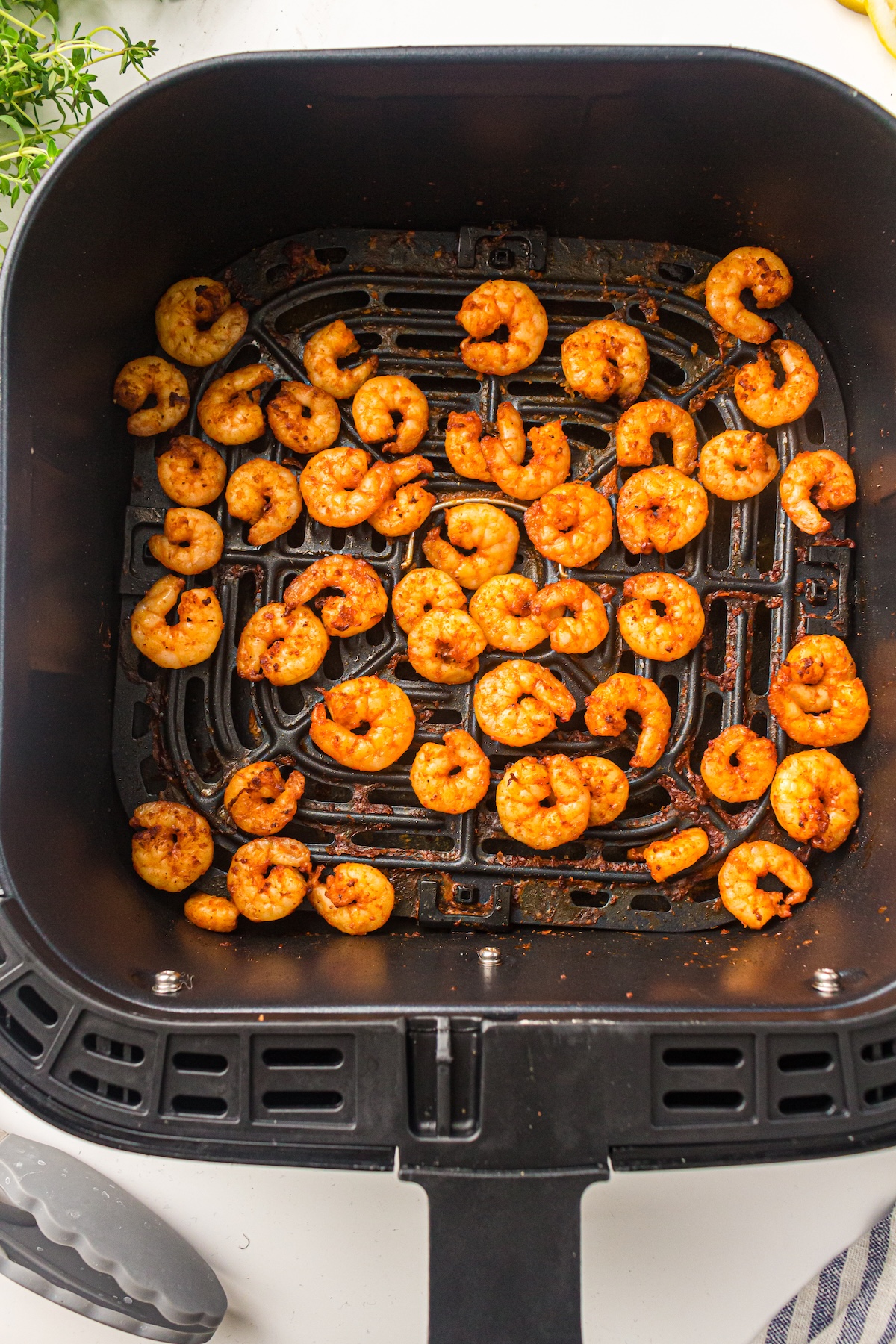 Golden-brown air fryer shrimp in a basket, perfectly cooked with a light seasoning of paprika and garlic.