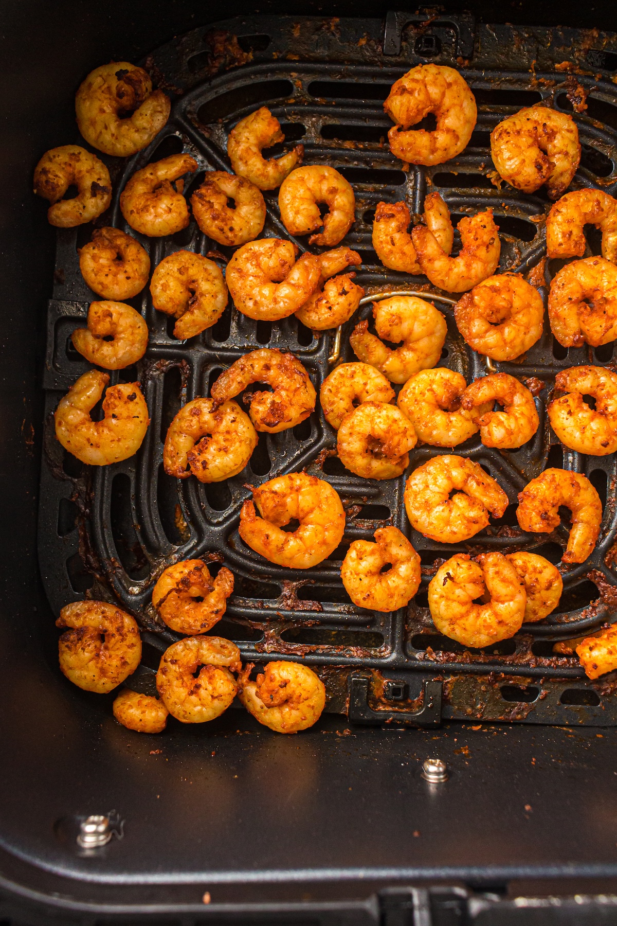 Golden-brown air fryer shrimp in a basket, perfectly cooked with a light seasoning of paprika and garlic.