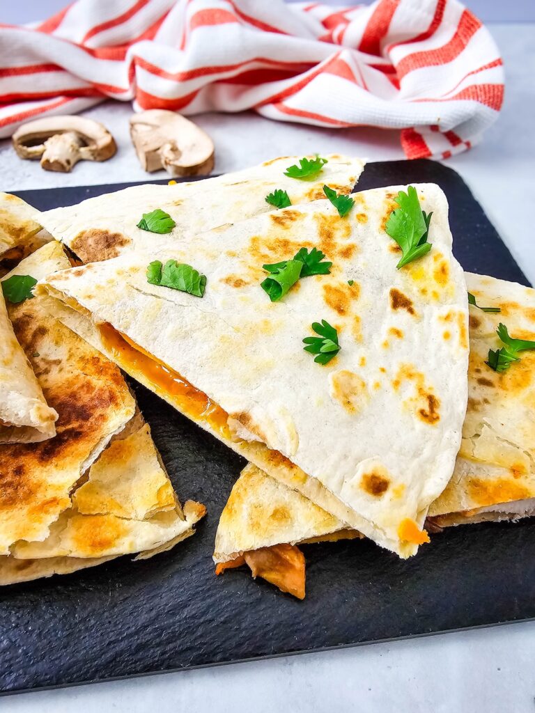 Chicken quesadilla wedges stacked showing golden tortilla and cheesy filling up close.