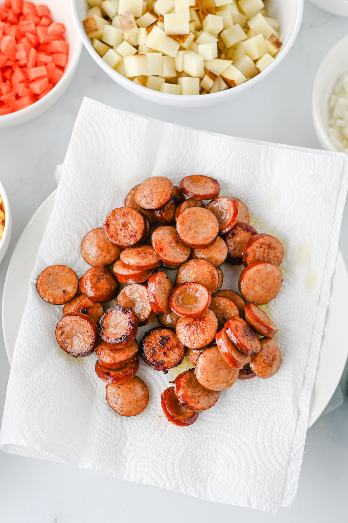 Crispy browned kielbasa sausage slices draining on a paper towel after searing.