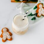 Iced gingerbread chai latte on a marble counter with gingerbread cookies and a Christmas tree towel