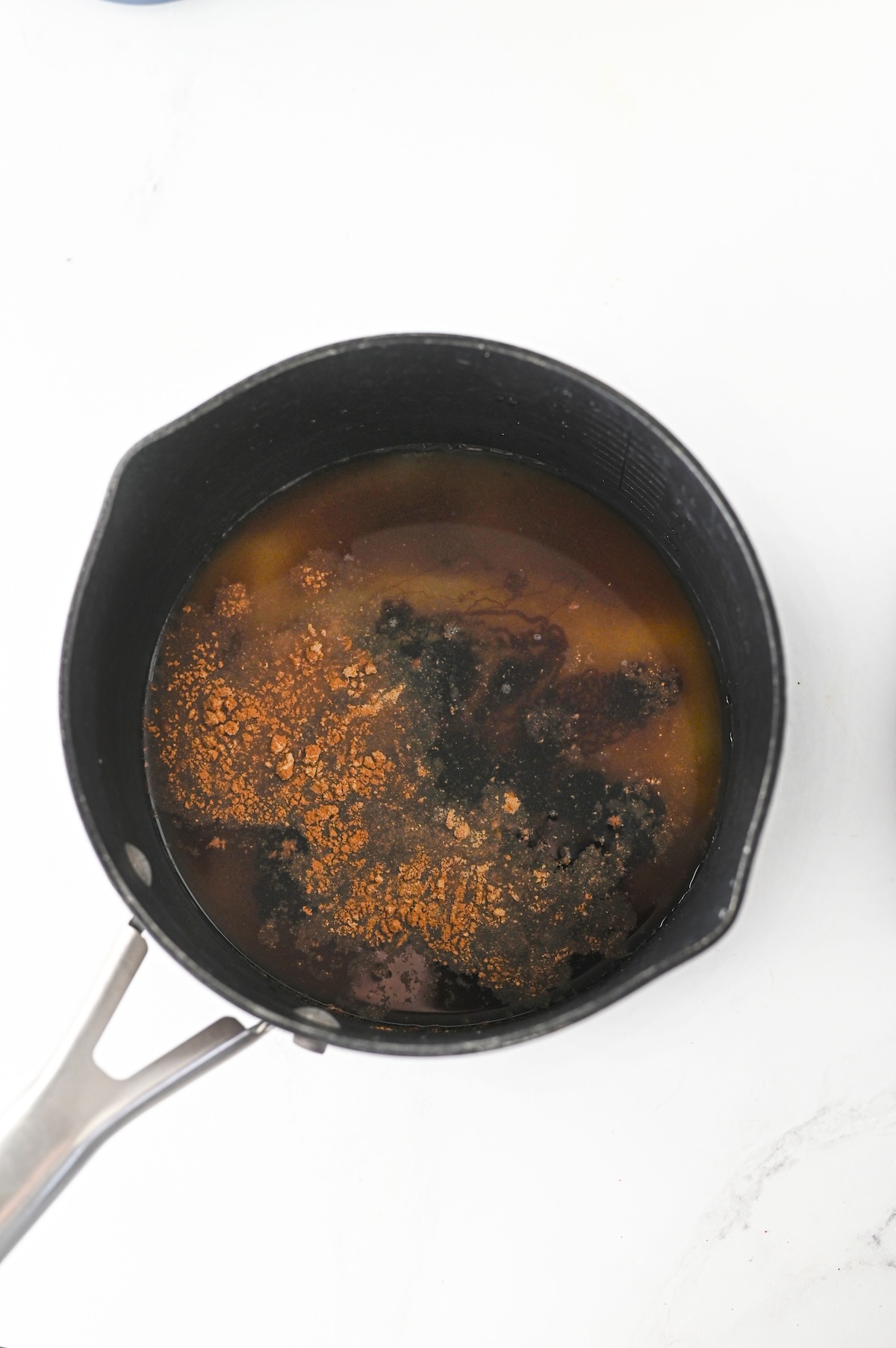 Brown sugar, granulated sugar, water, molasses, and spices combined in a saucepan for homemade gingerbread syrup