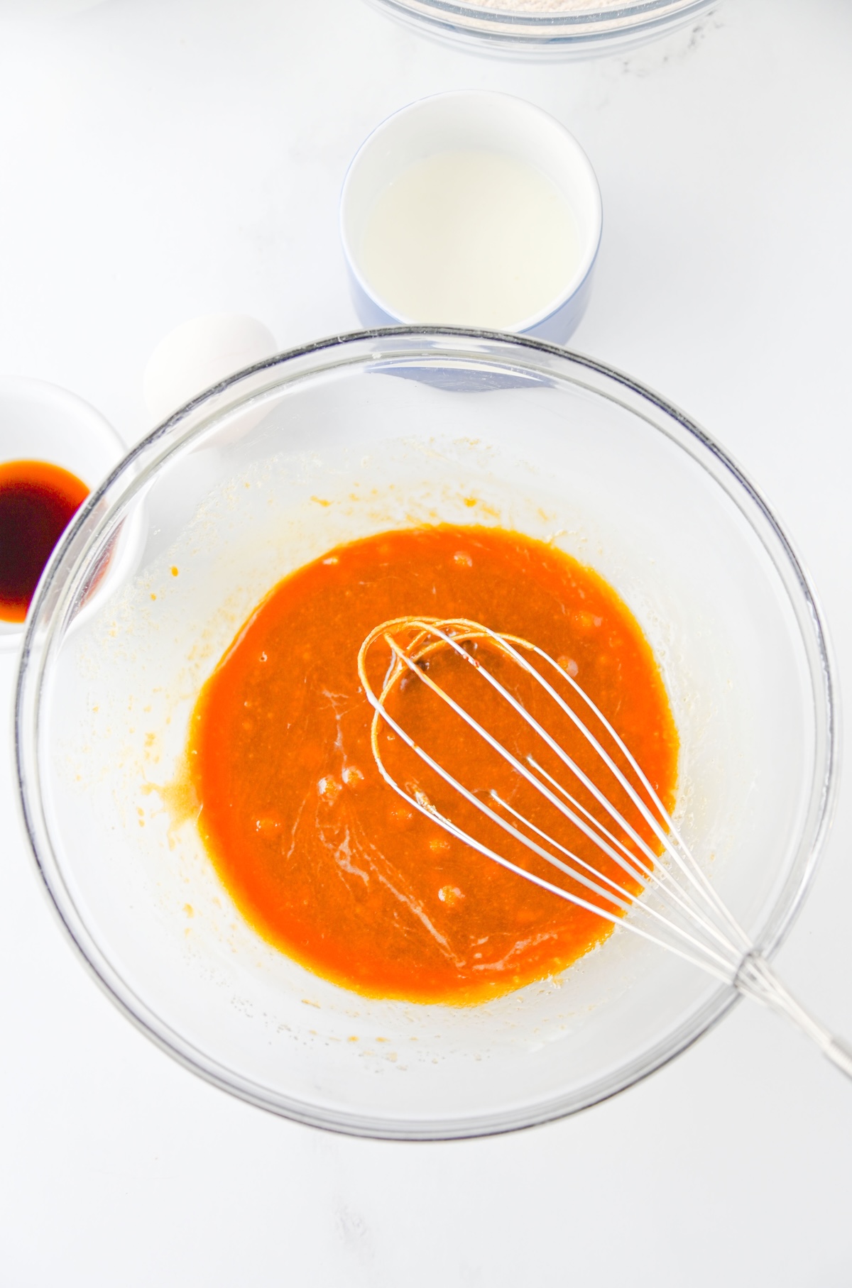 Wet ingredients for gingerbread whoopie pies being whisked together in a glass bowl