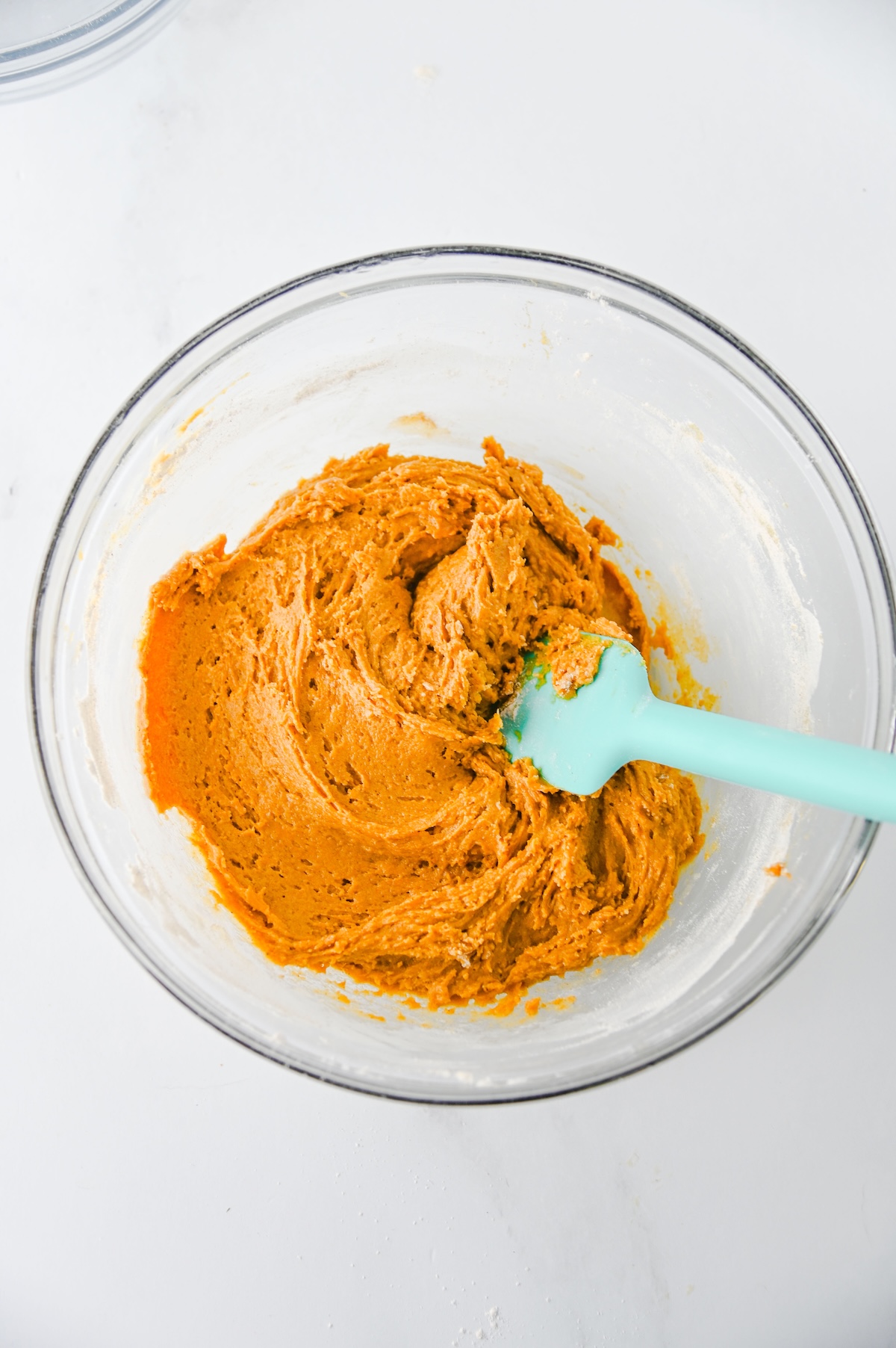 Thick gingerbread whoopie pie batter mixed with a spatula in a glass bowl