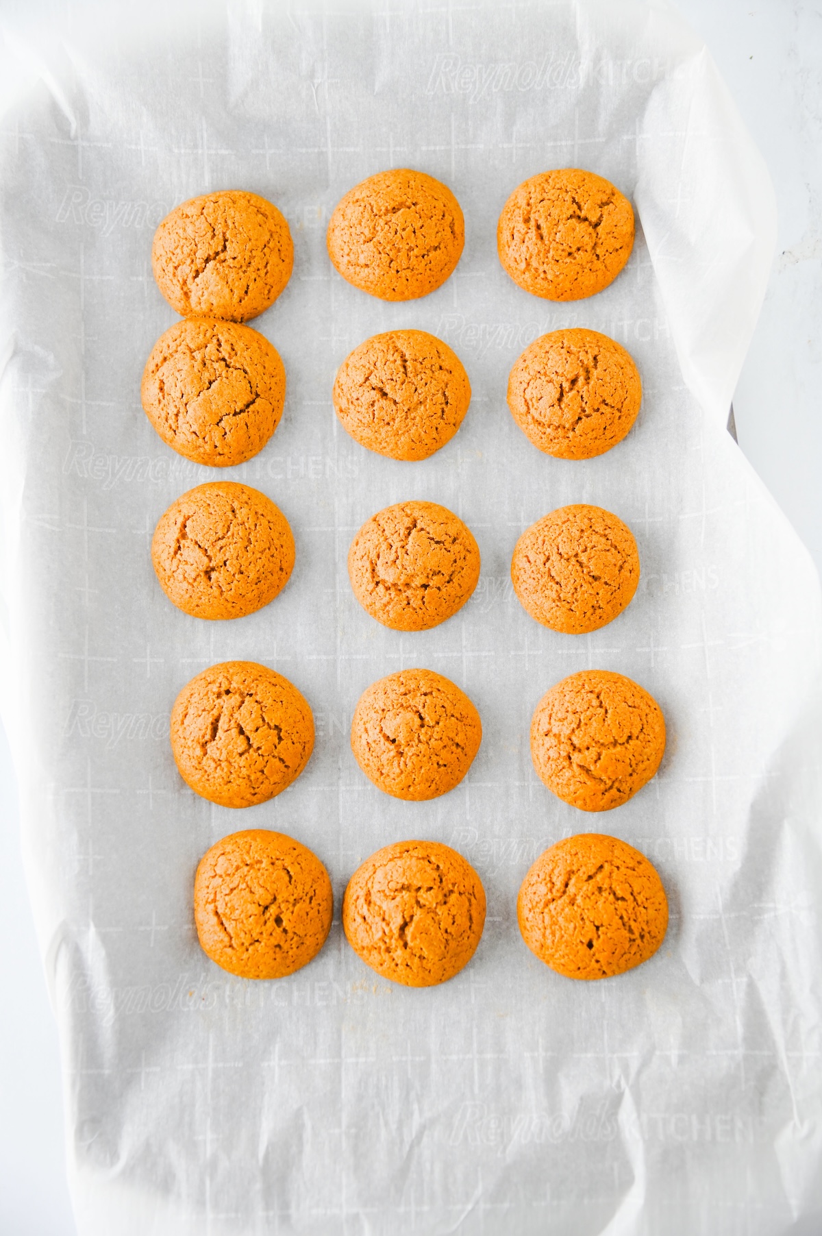 Baked gingerbread cookies for whoopie pies lined up on a parchment-lined baking sheet