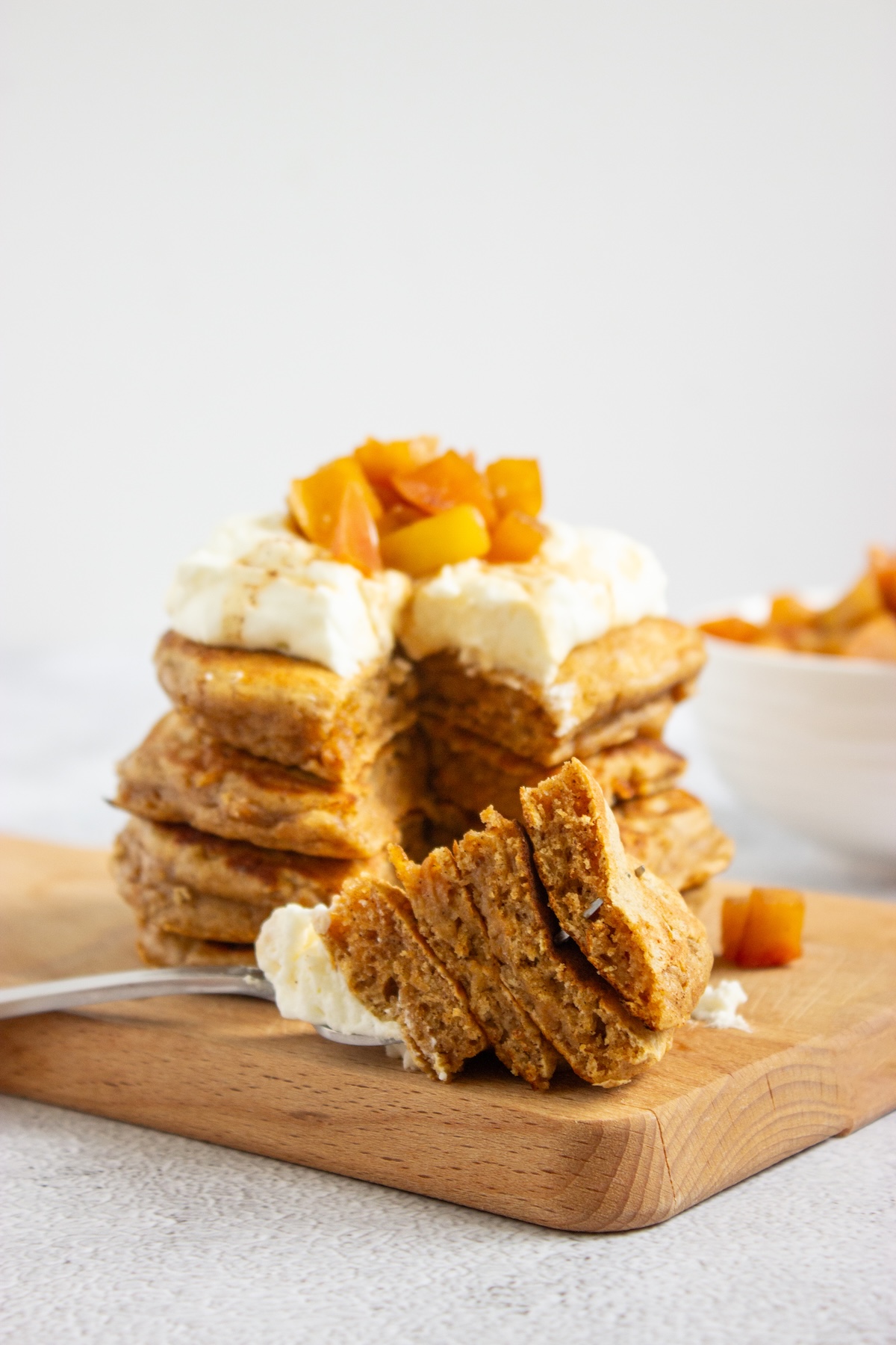 Side view of apple cinnamon pancakes with a wedge cut out showing the fluffy inside, topped with caramel apple compote