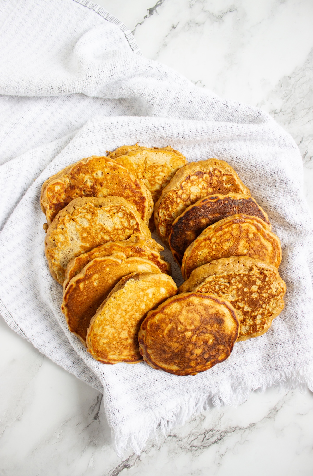 Golden apple cinnamon pancakes piled on a white kitchen towel