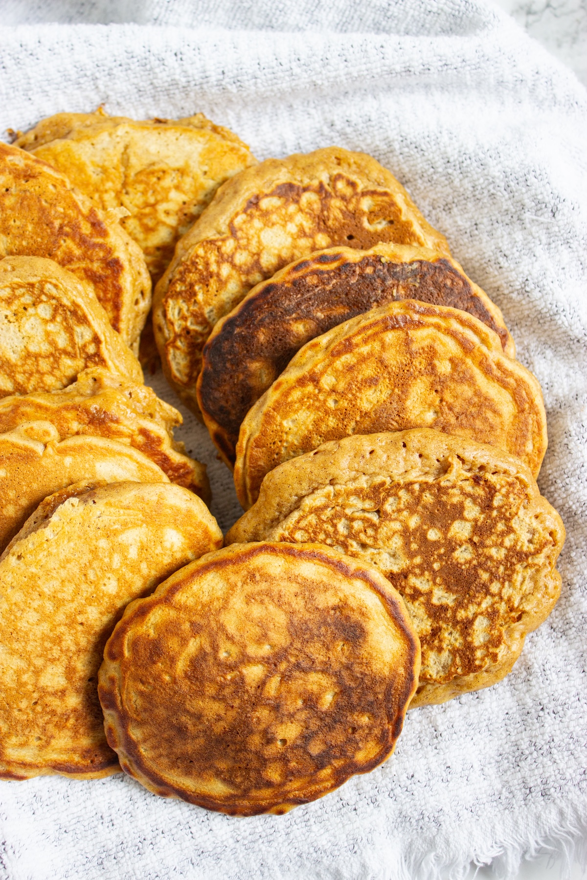 Close-up of golden brown apple cinnamon pancakes on a white kitchen towel
