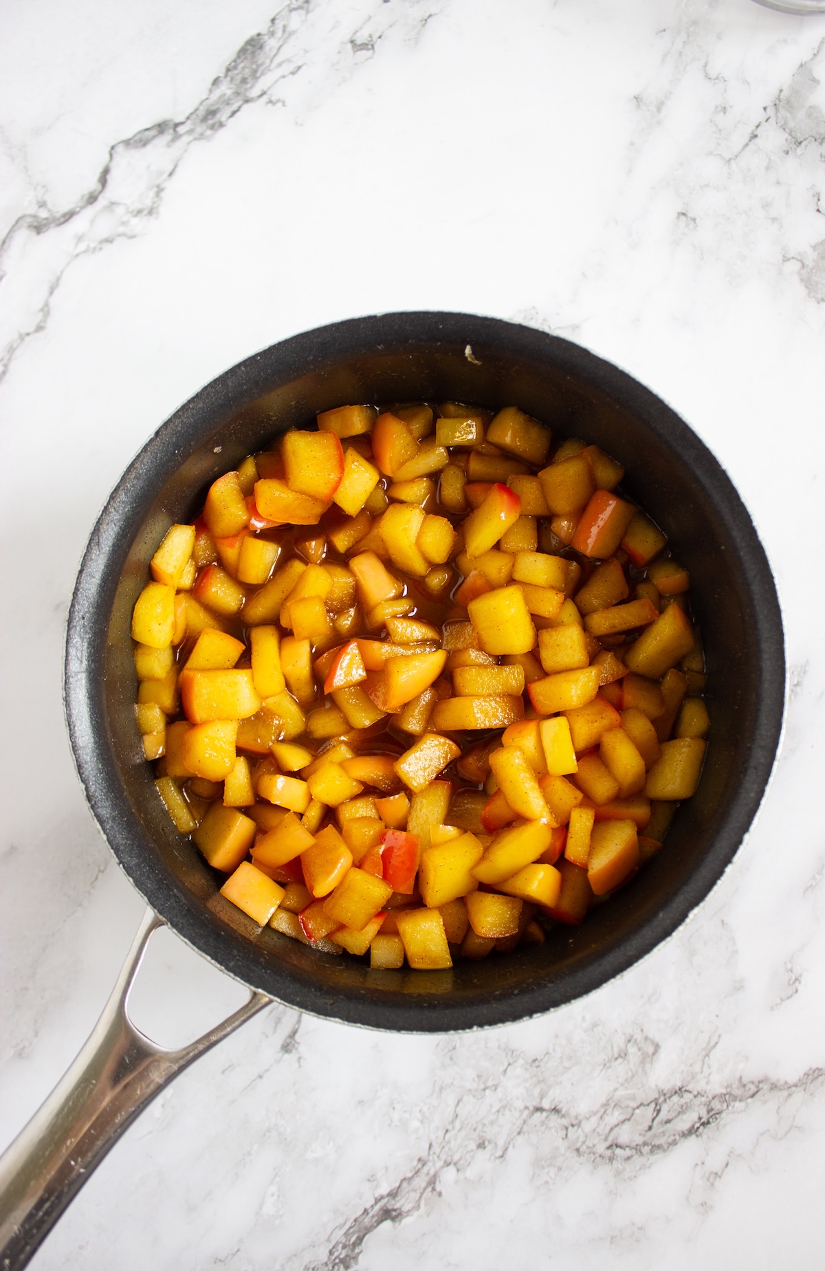 Finished caramel apple compote with tender, glossy apples in a saucepan