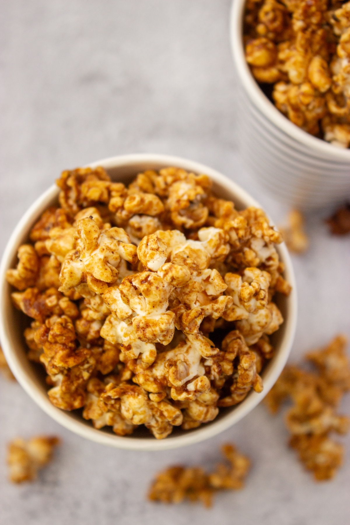 Close-up of glossy brown butter maple popcorn clusters in a striped cup