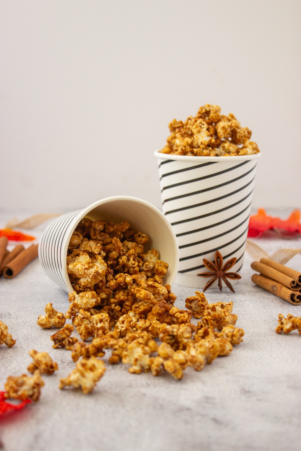 Tipped-over cup spilling brown butter maple popcorn onto a gray surface