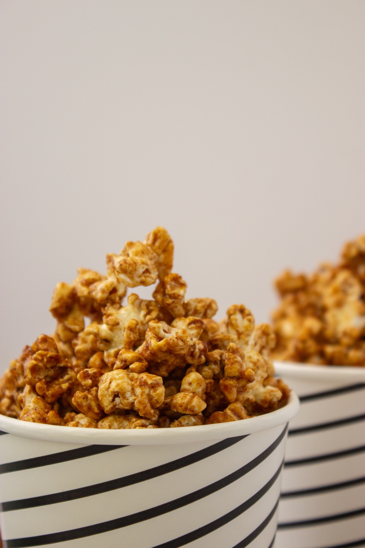 Close-up of caramelized maple popcorn overflowing a striped paper cup