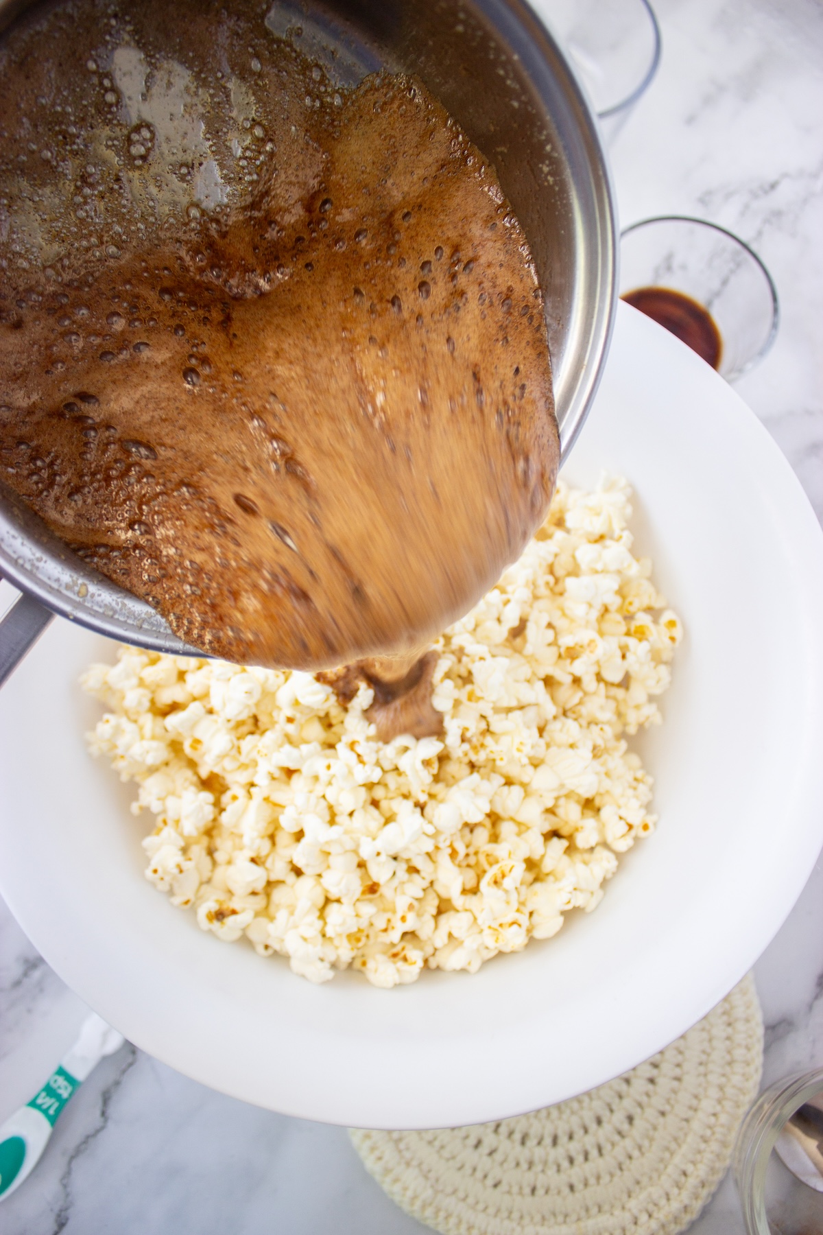 Brown butter maple caramel poured over popcorn in a large white bowl