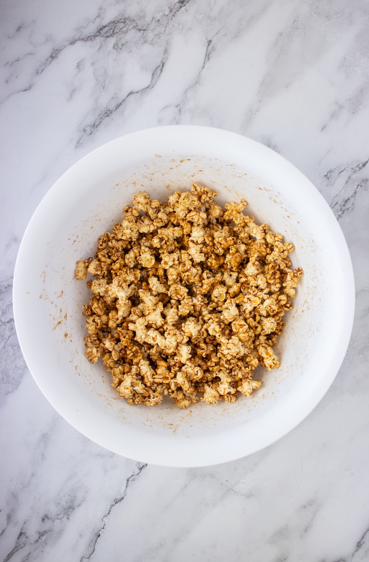 Popcorn tossed in brown butter maple caramel in a white bowl