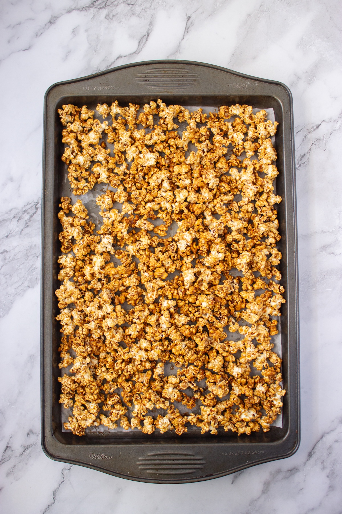 Brown butter maple popcorn spread on a baking sheet after baking