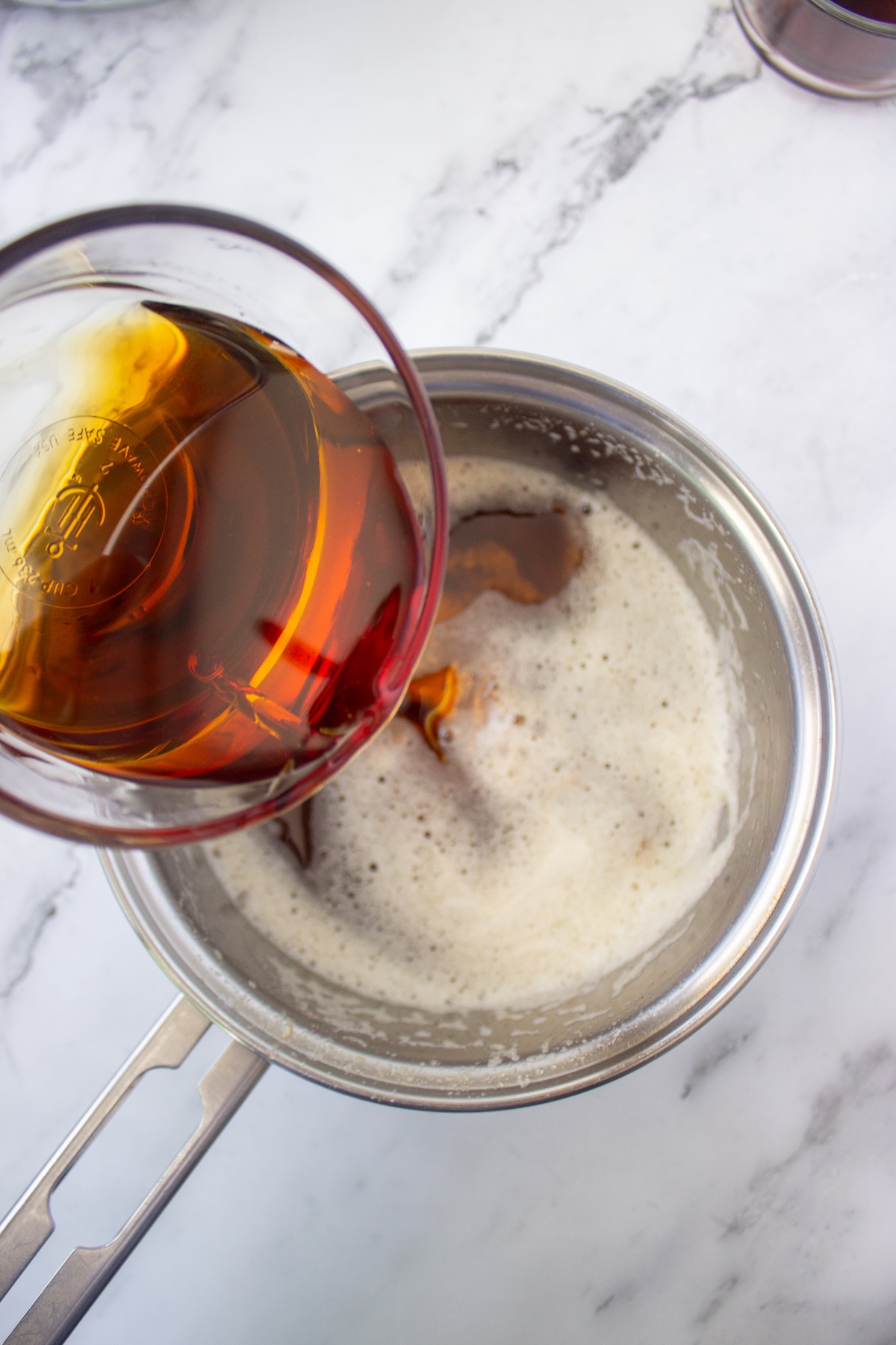 Maple syrup poured into brown butter in a saucepan