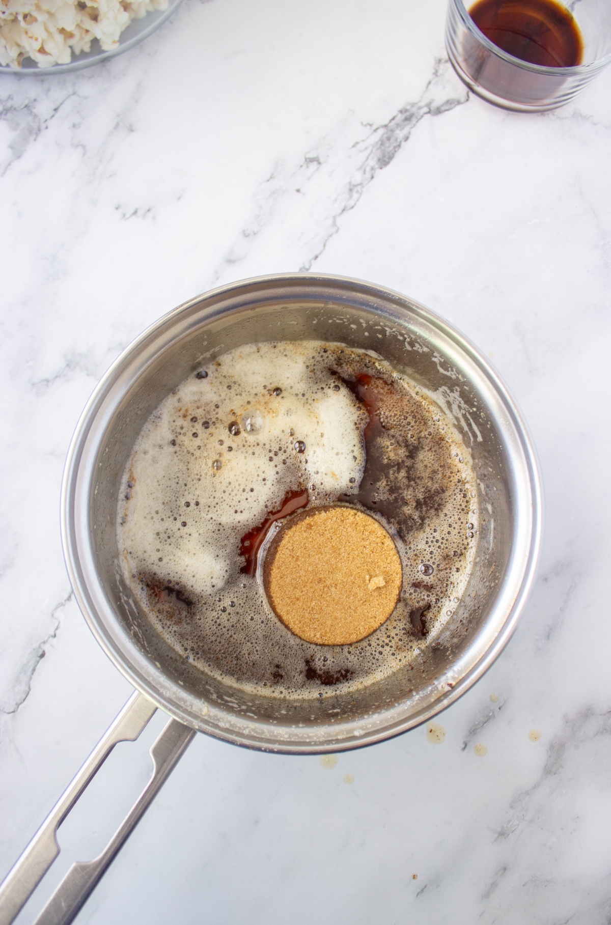 Brown sugar sitting on top of brown butter and maple syrup in a saucepan