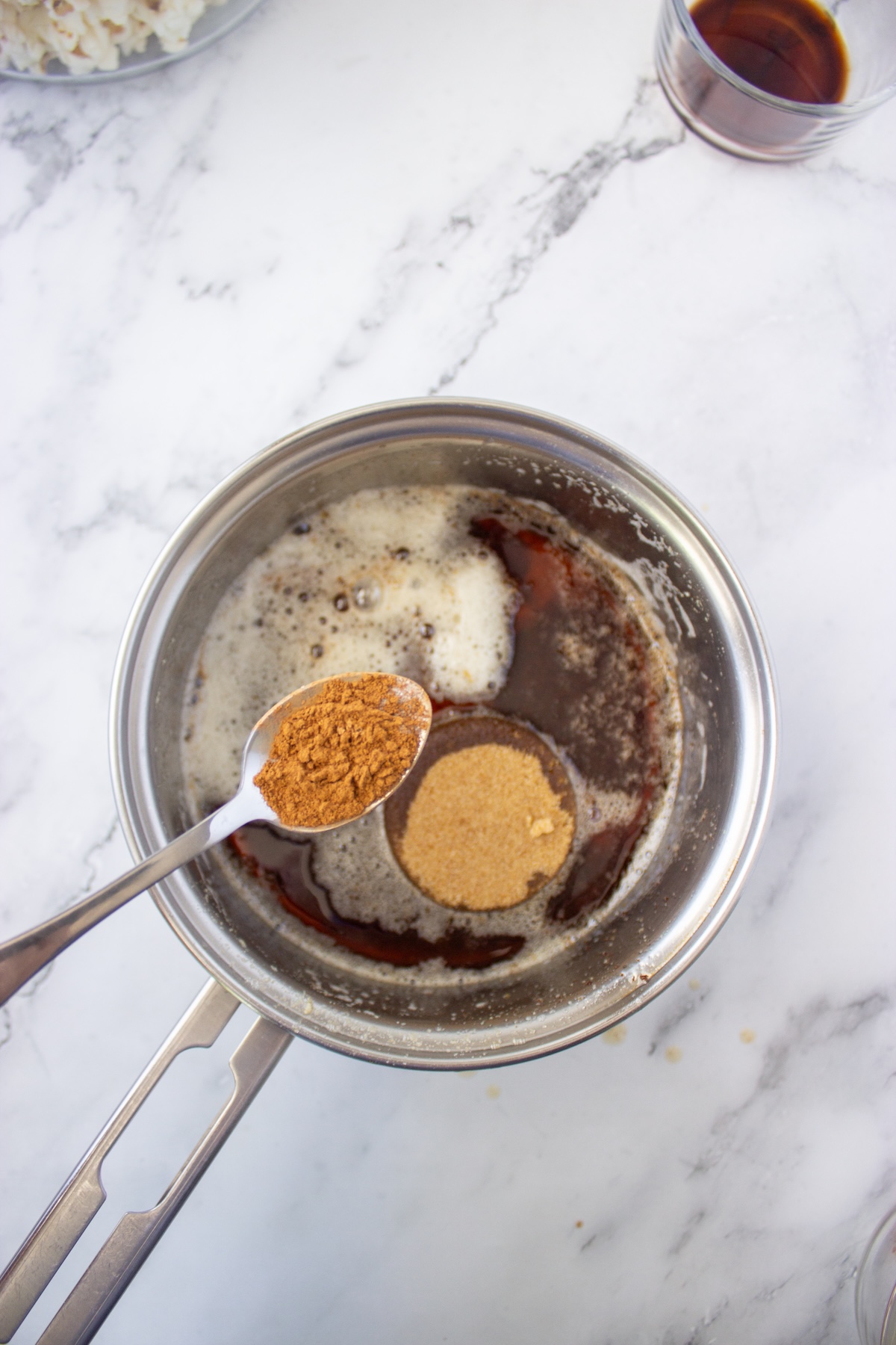Spoonful of spice added to the maple brown sugar mixture in a saucepan