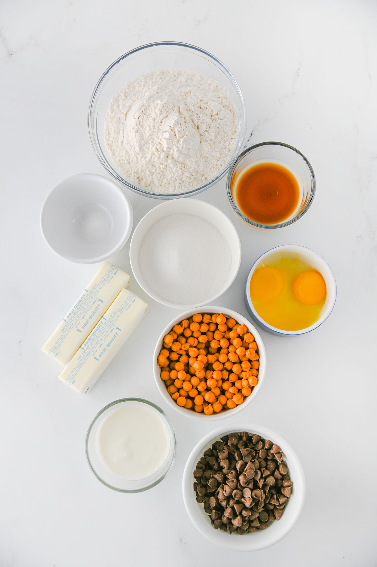 Ingredients for Twix thumbprint cookies including flour, sugar, butter, egg yolks, vanilla, caramel bits, cream, and chocolate chips
