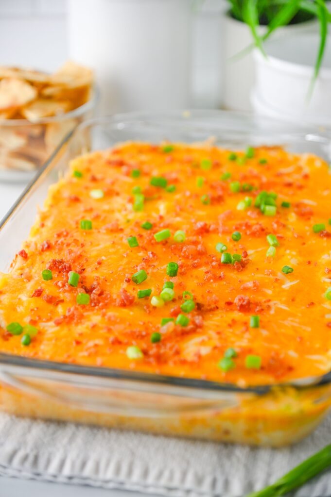 Crack chicken dip in a glass baking dish served with pita chips
