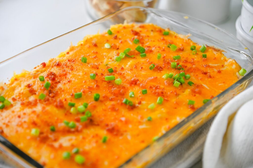 Side view of bubbly baked crack chicken dip topped with bacon and green onions